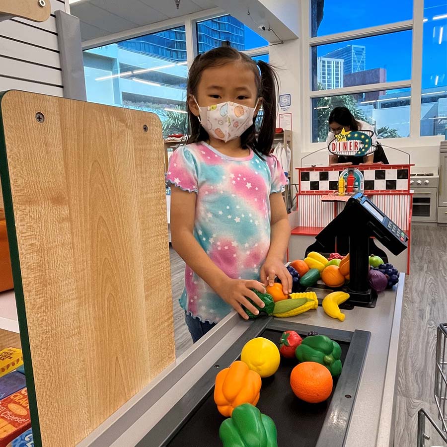 image of preschool student from Hongwanji Mission School learing about grocery stores with school playset